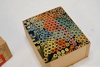 Top view of a box packed full of rolled horoscope scrolls in assorted pastel colors, showing an organized set of vintage horoscope scrolls.