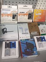 Photo of the lot showing ten different pairs of wireless earbuds and headsets in their factory packaging, arranged side by side and stacked in some places on a shelf.