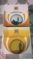 Two boxed binoculars with outdoor activity themed graphics in white and yellow packaging
