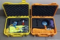 Two open hard cases with fishing magnets and accessories, arranged in foam padding; one case yellow, the other orange.