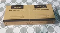 Two factory-boxed HDCVI digital video recorders side by side on a tiled surface, boxes showing model and branding.