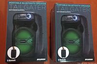 Photo showing two boxed Sylvania Portable Bluetooth Tailgater speakers side by side, front packaging visible.