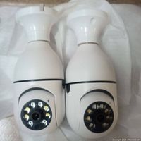 Front view of two white security cameras showing lens and infrared LEDs in circular pattern