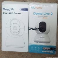 Front view of two security camera boxes sealed in original packaging, one Mienggood and one Blurams Dome Lite 2