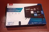 Photo of the TCL 32-inch Roku TV box showing the front side with Roku app interface and remote included.