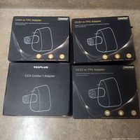 Four factory sealed boxes of electric car charger adapters, three Canashow brand CCS1 to TPC adapters and one TEPLUS CCS Combo 1 adapter, shown on a concrete floor.