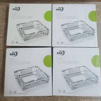 Four boxed glass ashtrays stacked together showing front of the boxes with product image and branding.