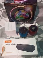 Group photo showing five Bluetooth speakers and LED music control light on checkered background.