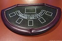 Full view of the blackjack table showing padded burgundy vinyl edges and printed blackjack game layout on black surface.