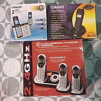 Photo showing the three boxed cordless phone systems from VTech, Casio, and GE, each in factory packaging.