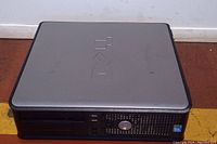 Front and top side view of a silver and black Dell desktop computer tower with visible Dell logo on top and front panel.