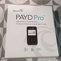Front of the Moneris PAYD Pro box showing branding, device name, and payment types supported.