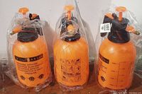 Three orange 2-liter pressure sprayers in factory packaging, side-by-side front view showing brand and capacity information.