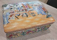 Large ceramic box with hand-painted Asian scene and floral decorative borders on lid and sides, showing fine detail and vibrant colors.