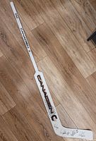 Full white Canadiens branded wooden goalie stick laid on a wood floor, showing overall condition and placement of signatures on the blade.