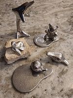 Photo showing all five vintage polished aluminum Hoselton sculptures arranged on a textured surface.
