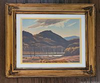 Framed lithograph artwork of a mountain and creek landscape with trees and clouds, signed by the artist.