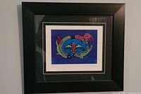 Framed artwork showing entire 'Metamorphosis Pisces' print by David Morrisseau in black frame with black and white matting.