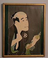 Framed full view of the antique Japanese woodblock print showing the figure with traditional clothing and ornamental object.