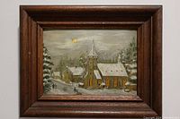 Framed original winter scene painting showing church and snow-covered buildings, trees, and path.