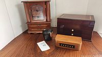Four wooden jewelry boxes and a black/brown decorative container on wooden surface against corner walls.