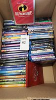 Photo showing the full collection of 56 kids Blu-ray and DVD movies in a box, including The Incredibles steelbook tin and Cars steelbook at the edges.