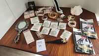 Photo of multiple new wedding and special occasion accessories arranged on a wooden table including hair accessories, jewelry, and a handheld mirror.