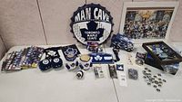 Overview of Toronto Maple Leafs collectibles including signs, bobbleheads, and assorted fan merchandise arranged on a table.