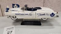 Side view showing Toronto Maple Leafs decals and flags on the white diecast convertible model car mounted on a display stand.