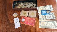 Overview of lot showing coins in wooden box, Canadian banknotes and collectible coin card