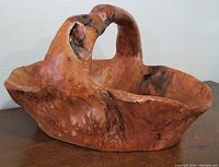 Carved burled wood basket with handle shown from front and side angles