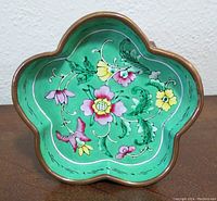 Top view of a flower-shaped cloisonne dish with green background and multicolor floral patterns