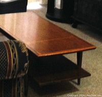 Photo of a wooden rectangular coffee table with a smooth top and a lower shelf underneath for storage.