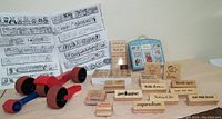 Various wooden handle rubber stamps with greeting messages, and three red handle rolling stamps arranged on table with decorative paper and stamp guidelines behind.