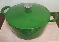 Closed green enameled Dutch oven with lid, showing shiny finish and metal knob.