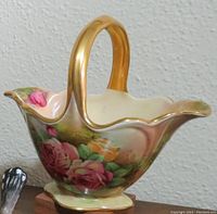 Porcelain floral basket with gold handle and rose motif, showing delicate hand painted roses and gold trimming.