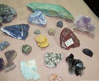 Top view of assorted rocks and mineral specimens of various colors, textures, and sizes on a flat surface.