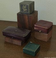 Five vintage jewelry boxes grouped together on wooden stands showing different shapes and colors.