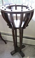 Photo of dark wooden open basket-style plant stand with grooved legs and crossbase