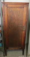 Front view of closed antique wooden cabinet showing door and keyhole lock