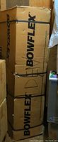 Five stacked cardboard boxes branded BOWFLEX, sealed with black straps