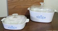 Two CorningWare dishes in cornflower pattern, one large rectangular Dutch oven with lid and one smaller square Dutch oven with lid