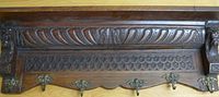 Front view of carved wooden coat rack showing five hooks and decorative carving