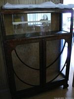 Front view of the antique display cabinet showing wooden frame, glass panels on three sides, decorative circular wooden trim on the front glass doors, and glass shelves inside the lower portion.
