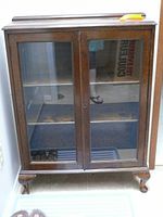 Front view of oak cabinet showing glass-front double doors, two shelves, and cabriole legs