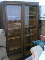 Side view of taller wooden display cabinet with glass double doors and several interior shelves