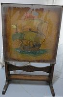 Front view of antique folding side table showing hand painted sailing ship on the top surface with aged crackling paint.