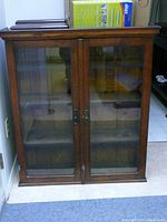 Front view of entire cabinet showing two glass-paneled doors, wood frame and metal handles