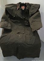 Olive green waxed cotton coat with storm cape and brown suede collar laid open