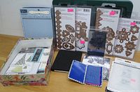 Photo showing the full lot arranged on a table including metal dies, embossing folder, stencil box, embossing tools, and needle case.